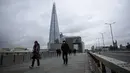 Orang-orang berjalan melintasi Jembatan London pada pagi pertama penerapan lockdown nasional ketiga di Kota London, Inggris, 5 Januari 2021. Inggris memasuki lockdown nasional ketiga sejak pandemi virus corona COVID-19 dimulai. (AP Photo/Matt Dunham)