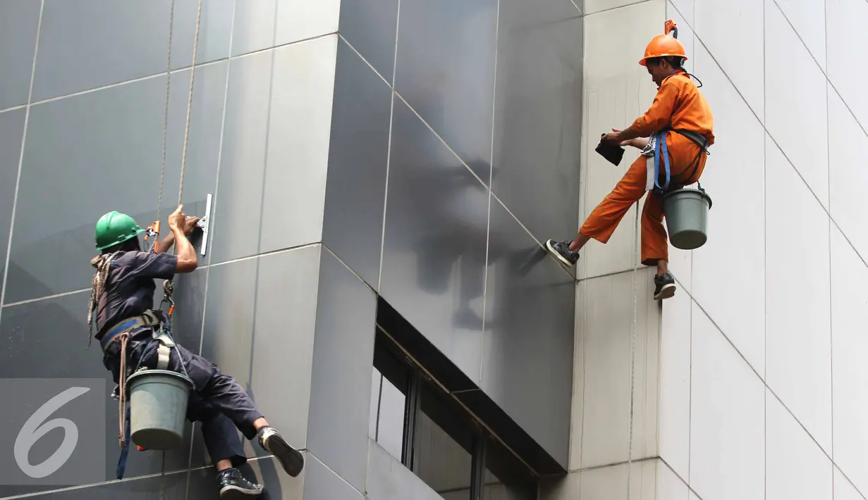 Dua pekerja membersihkan kaca gedung bertingkat di Jakarta, Senin (25/8/2015). Untuk meminimkan kecelakaan, Kementerian Tenaga Kerja dan Transmigrasi telah mencanangkan bulan Keselamatan dan Kesehatan Kerja (K3) pada 2014. (Liputan6.com/Helmi Afandi)