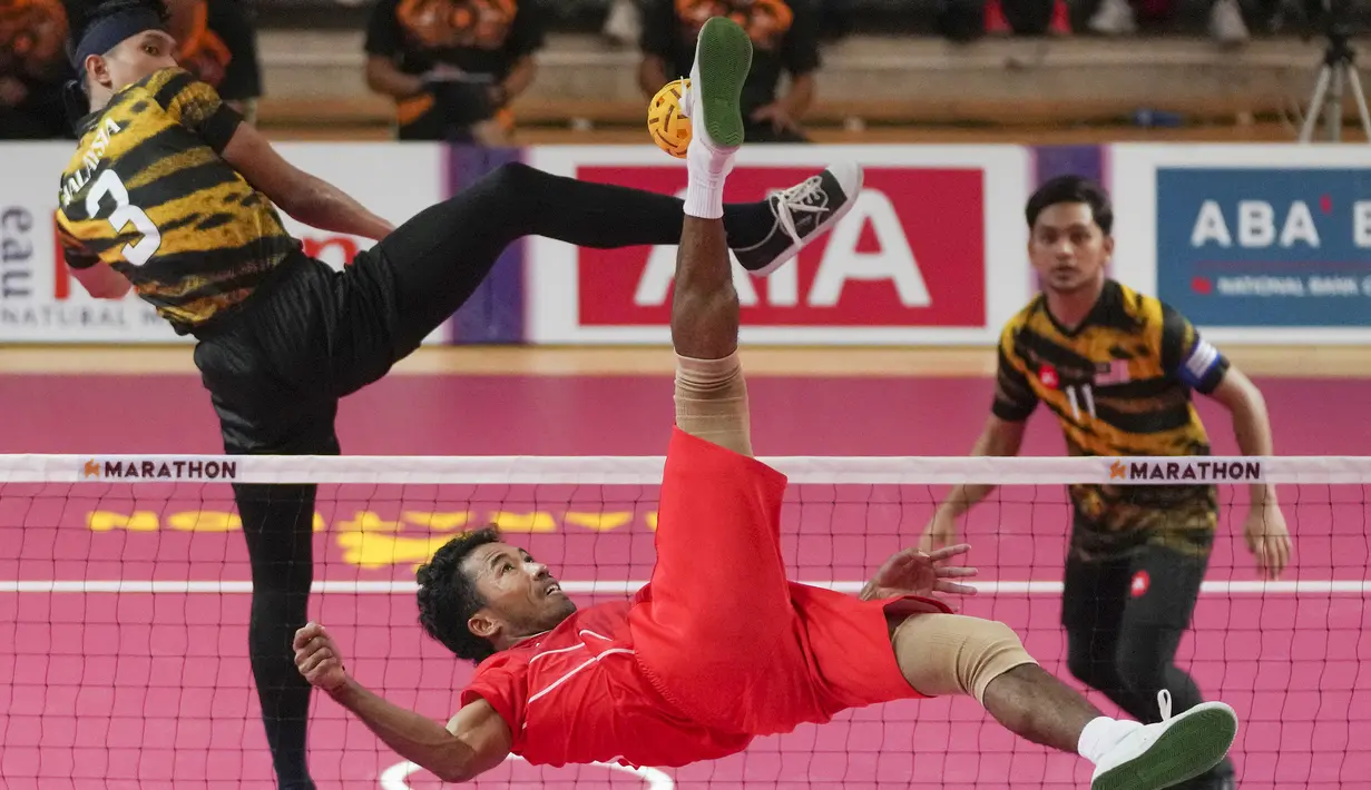 <p>Pemain Tim Sepak Takraw Indonesia, Rusdi menendang bola ke arah Tim Sepak Takraw Malaysia pada laga final nomor ganda putra perorangan sepak takraw SEA Games 2023 di Olympic Stadium, Phnom Penh, Kamboja, Senin (15/05/2023). Indonesia berhasil menang dengan skor skor 14-21, 21-16, dan 21-13. (AP Photo/Tatan Syuflana)</p>