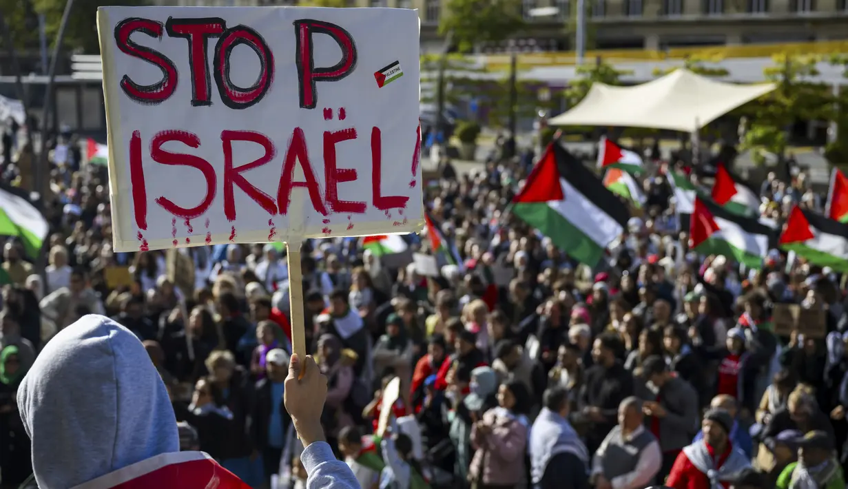 Para pengunjuk rasa memegang poster dan bendera Palestina selama unjuk rasa pro-Palestina, di Lausanne, Swiss, Sabtu, 21 Oktober 2023. (Jean-Christophe Bott/Keystone via AP)