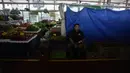 Seorang pedagang duduk di depan kiosnya yang bertirai berharap pengiriman produknya tiba di sebuah pasar di Panama City, Rabu (20/7/2022). Protes minggu ketiga dan blokade jalan raya mulai berdampak pada pasokan makanan dan barang-barang lainnya di beberapa bagian Panama. (AP Photo/Arnulfo Franco)