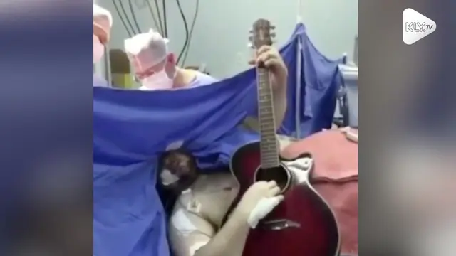 Seorang pria tetap santai walau sedang jalani operasi otak. Ia malah main gitar sambil bernyanyi lagu The Beatles yang berjudul 'Yesterday'.