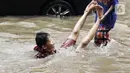Anak anak bermain air di sebagian Jalan Bungur Besar Raya yang tergenang, Jakarta, Selasa (18/1/2022). Genangan air di sebagian Jalan Bungur Besar Raya dimanfaatkan anak-anak untuk bermain meski berbahaya. (Liputan6.com/Helmi Fithriansyah)