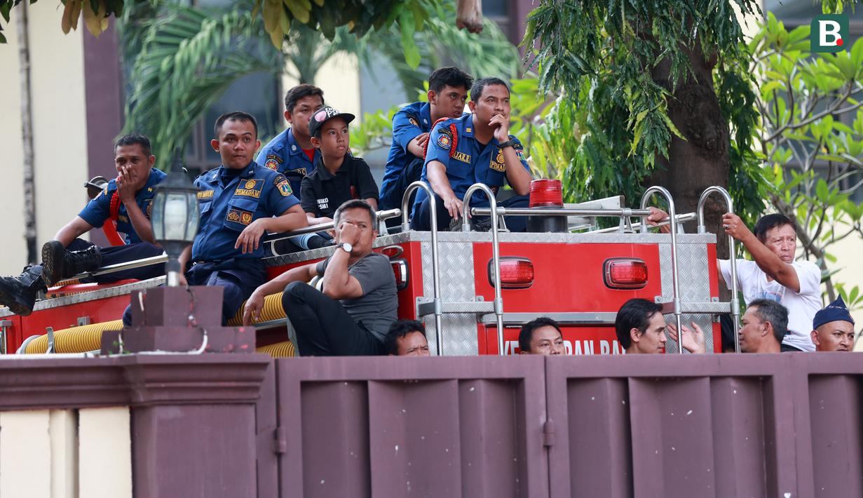 Petugas pemadam kebakaran menyaksikan pertandingan antara Arema FC melawan PSM Makassar pada laga BRI Liga 1 di Stadion PTIK, Jakarta, Sabtu (4/2/2023). Namun sejumlah pekerja petugas yang berdinas di sekitar komplek STIK bisa menyaksikan laga tersebut dari luar stadion. (Bola.com/M Iqbal Ichsan)