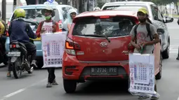 Pedagang menawarkan kalender tahun 2021 kepada pengguna jalan di perempatan Pondok Pinang, Kebayoran, Jakarta Selatan, Senin (7/12/2020). Jelang pergantian tahun, sejumlah pedangang mulai menjajakan kalender tahun 2021 dengan harga Rp 20 ribu-Rp 40 ribu tergantung ukuran. (merdeka.com/Dwi Narwoko)