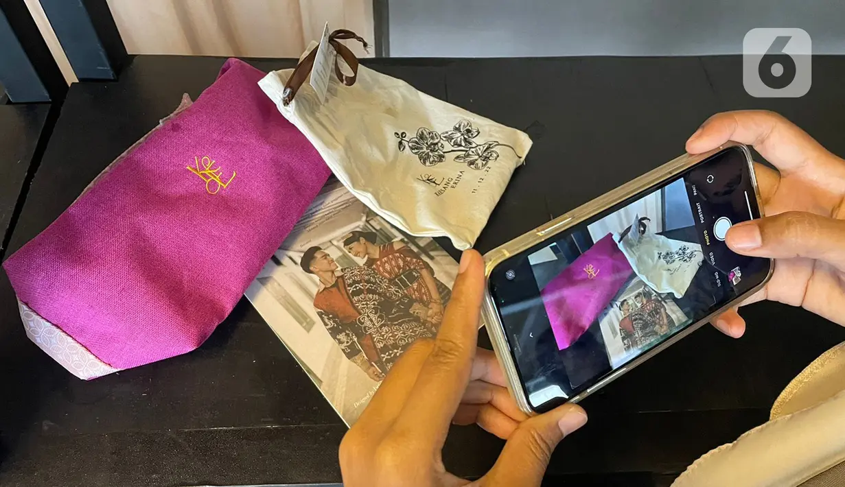 Tamu undangan mendapatkan souvenir pernikahan Kaesang Pangarep dan Erina Gudono di Pura Mangkunegaran, Solo, Minggu (11/12/2022). Antrean tamu undangan yang ingin berfoto dengan Kaesang Pangarep dan Erina Gudono beserta keluarga mengular panjang bahkan rela berdesak-desakan demi bisa berfoto dengan kedua mempelai. (Liputan6.com/Herman Zakharia)