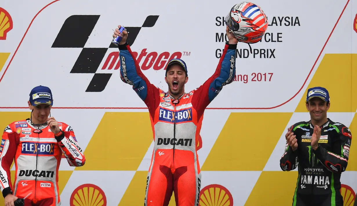 Pembalap Ducati Team, Andrea Dovizioso mengangkat helmnya bersama Jorge Lorenzo dan Johann Zarco di atas podium setelah memenangkan MotoGP Malaysia di sirkuit Sepang, Minggu (29/10). Dovizioso keluar sebagai juara MotoGP Malaysia (Manan VATSYAYANA / AFP)