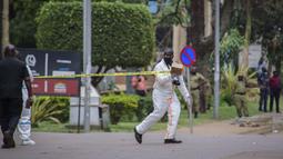 Seorang petugas forensik mengamankan lokasi ledakan di sebelah kantor polisi pusat di Kampala, Uganda (16/11/2021).  Serangan yang terjadi di dekat parlemen Uganda dan markas polisi terjadi hampir bersamaan dengan selisi kurang dari tiga menit. (AP Photo/Nicholas Bamulanzeki)
