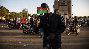 Pendukung gerakan Save Burkina Faso memegang bendera nasional setelah Letnan Kolonel Paul Henri Sandaogo mengumumkan telah mengambil alih kendali negara di Ouagadougou, Senin (24/1/2022). Militer Burkina Faso mengklaim berhasil mengambil alih pemerintahan dan mengudeta presiden. (AP/Sophie Garcia)