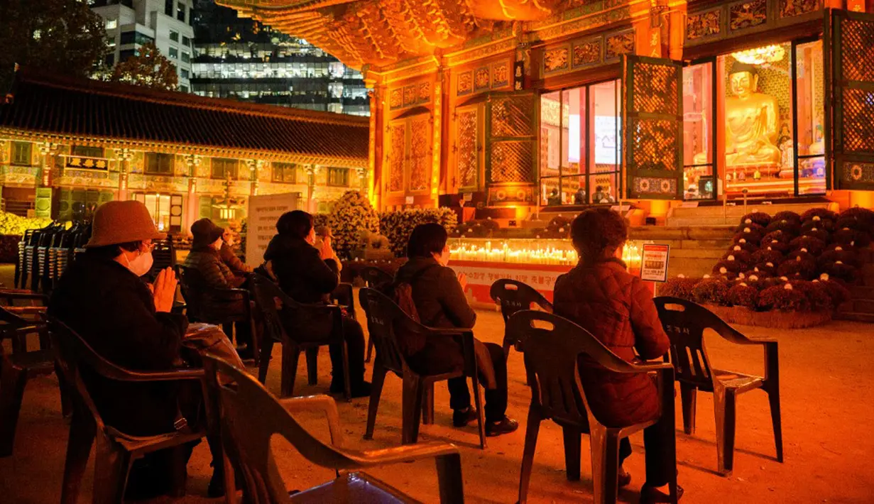 Warga berdoa di Kuil Jogyesa pada malam sebelum para siswa mengikuti ujian masuk universitas atau suneung, Seoul, Korea Selatan, 17 November 2021. Lebih dari setengah juta siswa akan mengikuti suneung di Korea Selatan. (Anthony WALLACE/AFP)