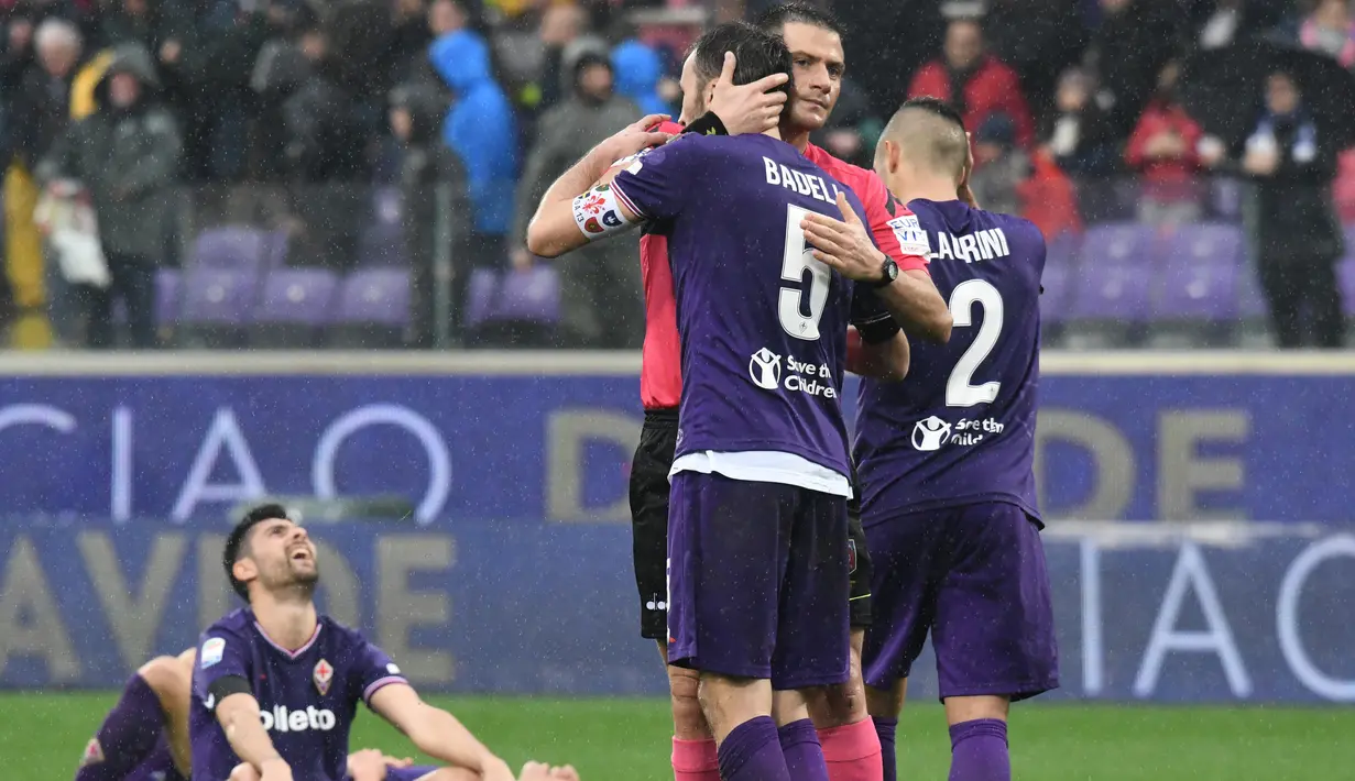 Wasit Fabrizio Pasqua memeluk kapten baru Fiorentina Badelj usai pertandingan di stadion Artemio Franchi di Florence (11/3). Suasana haru menyelimuti pertandingan usai Fiorentina ditinggal sang kapten, Davide Astori. (AFP Photo/Claudio Giovannini)