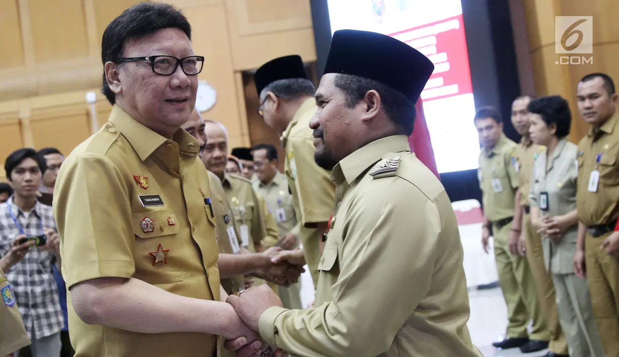 Mendagri, Tjahjo Kumolo (kiri) memberikan selamat kepada Plt Bupati Bener Meriah, Tgk. H. Sarkawi usai serah terima surat penugasan Pelaksana Tugas Gubernur Aceh dan Bupati Bener Meriah di Kemendagri Jakarta, Senin (9/7). (Liputan6.com/Herman Zakharia)