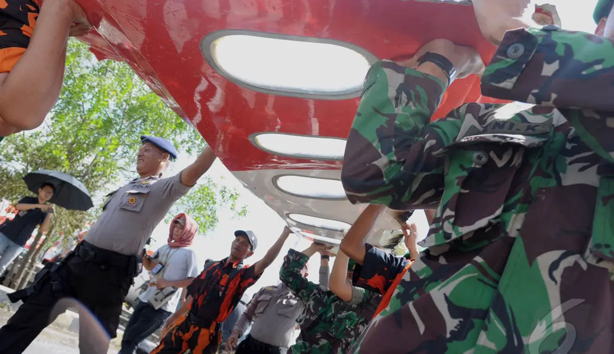 Petugas gabungan membawa bagian pesawat AirAsia QZ8501 yang sudah dipotong untuk segera dimasukan kedalam gudang penyimpanan di Pelabuhan Panglima Utar, Kumai, Kalimantan Tengah, Senin (12/01/2015). (Liputan6.com/Andrian M Tunay)