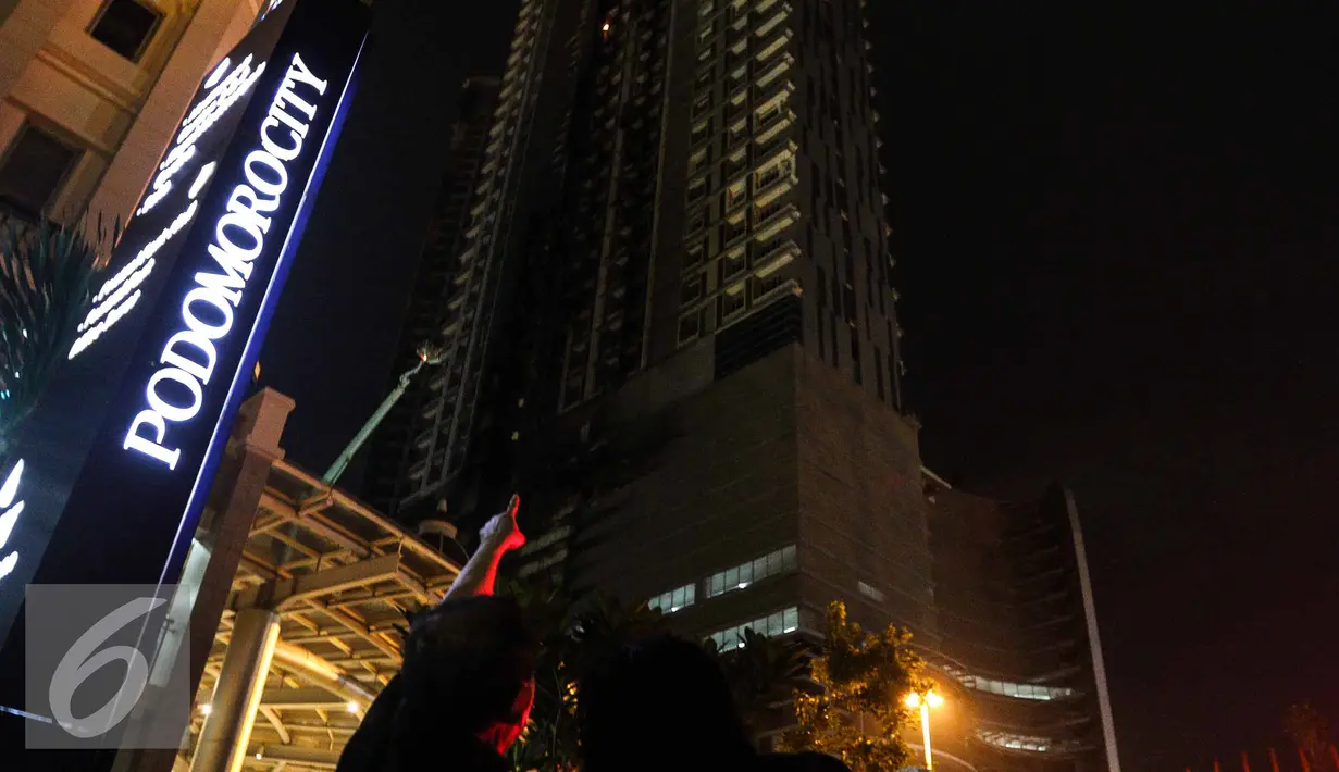 Warga menunjukkan titik api yang masih tersisa di Gedung Neo Soho, Jakarta Barat, Rabu (9/11). Gedung Neo Soho sempat terbakar hebat hampir di setiap lantainya. (Liputan6.com/Faizal Fanani)