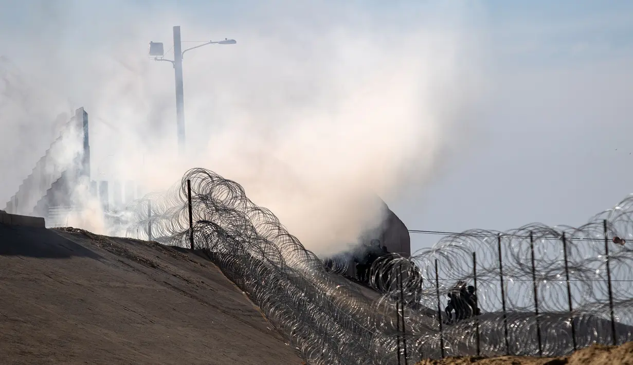 Gas air mata ditembakan petugas patroli perbatasan AS untuk membubarkan para imigran Amerika Tengah yang sebagian merupakan penduduk Honduras di perbatasan antara Meksiko dan AS di Tijuana, Meksiko (25/11). (AFP Photo/Guillermo Arias)