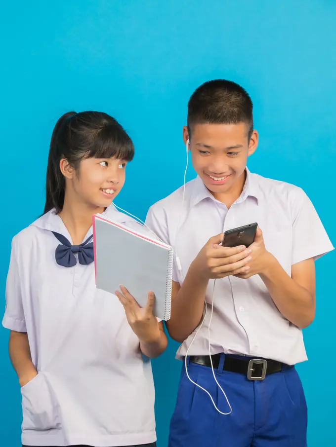 Dua orang siswa sedang mendengarkan HP bersama dengan menggunakan headset (Foto Dok: Freepik/jcomp)