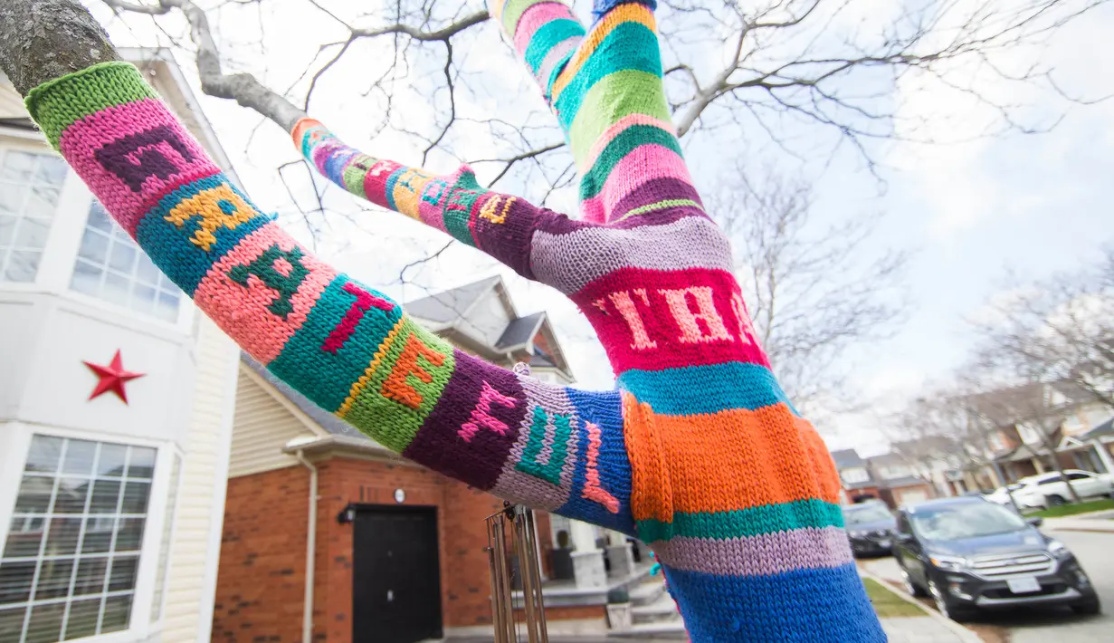 Sebuah pohon yang dibalut rajutan benang bertuliskan ucapan terima kasih untuk menghormati para pekerja garis depan yang tengah berjuang melawan COVID-19 terlihat di Burlington, Ontario, Kanada (19/4/2020). (Xinhua/Zou Zheng)
