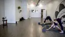 Pemilik Elyse DiBartolo (kanan) dan instruktur Brendan Smullen mengadakan kelas yoga online melalui webcam di Haus Yoga, H Street, Washington, Amerika Serikat, Selasa (17/3/2020). Kelas yoga online ini dilakukan setiap hari selama karantina virus corona COVID-19. (AP Photo/Andrew Harnik)