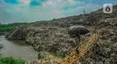 Warga membawa sampah daur ulang melewati lokasi longsor Tempat Pembuangan Akhir (TPA) Cipayung yang menutup Sungai Pesanggrahan di Depok, Jawa Barat, Selasa (30/4/2024).  (merdeka.com/Arie Basuki)