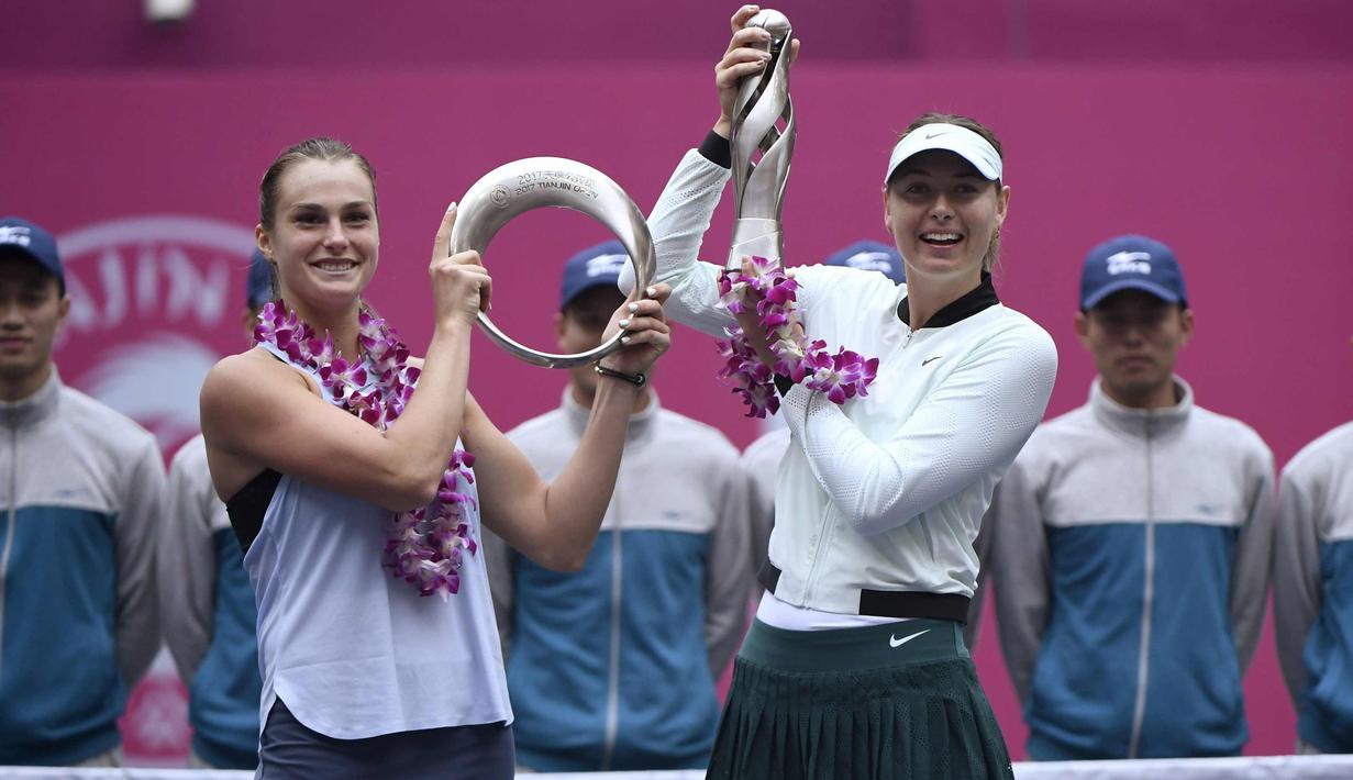 Maria Sharapova dan Aryna Sabalenka berpose dengan trofi mereka setelah bertanding pada final tunggal wanita melawan Aryna Sabalenka dari Belarus pada turnamen tenis Tianjin Open di Tianjin (15/10). (AFP Photo/Wang Zhao)