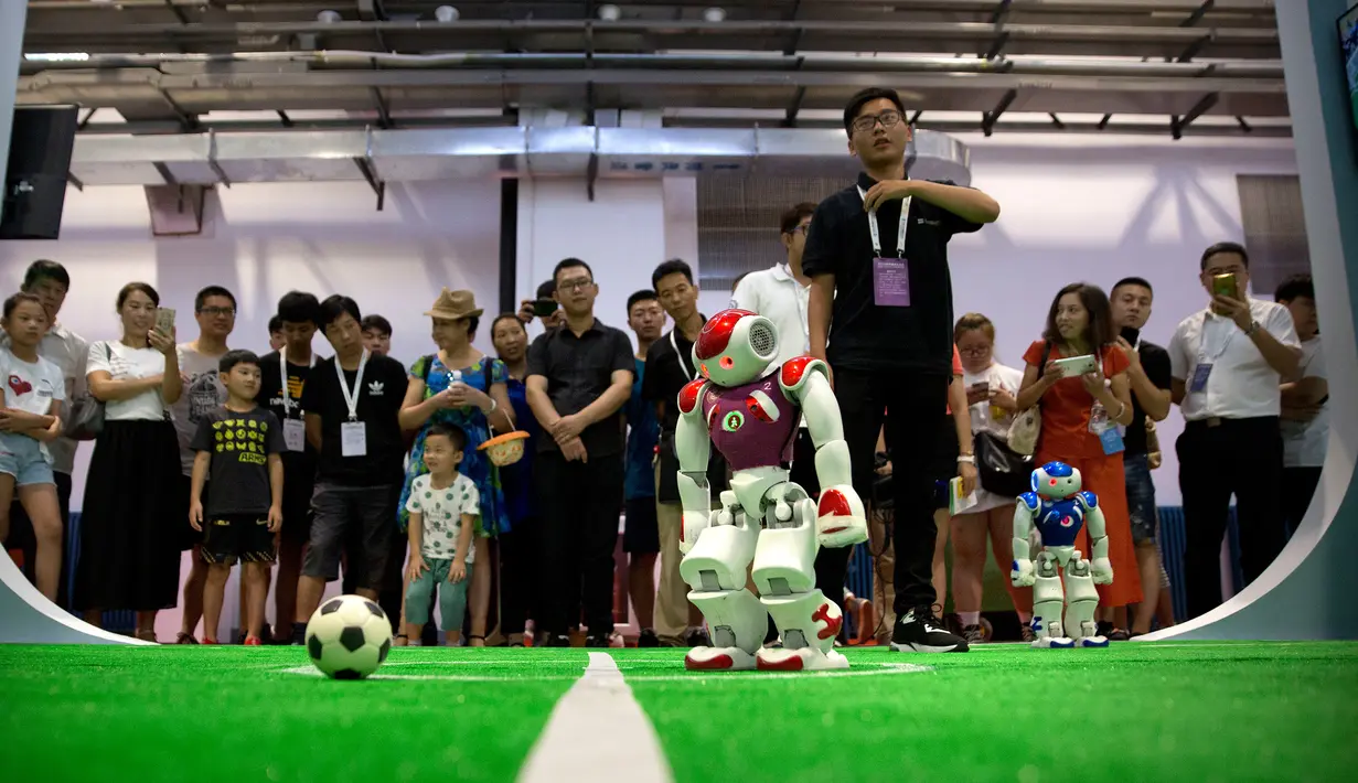 Pengunjung menyaksikan pertandingan sepak bola yang dimainkan oleh robot dari perusahaan teknologi Softbank pada Konferensi Robot Dunia di Beijing, China, Rabu (15/8). (AP Photo/Mark Schiefelbein)