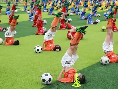 Para siswa beraksi dengan bola saat acara pembukaan sebuah turnamen sepak bola di Dalian, Liaoning, China, (16/7/2016). (Reuters)