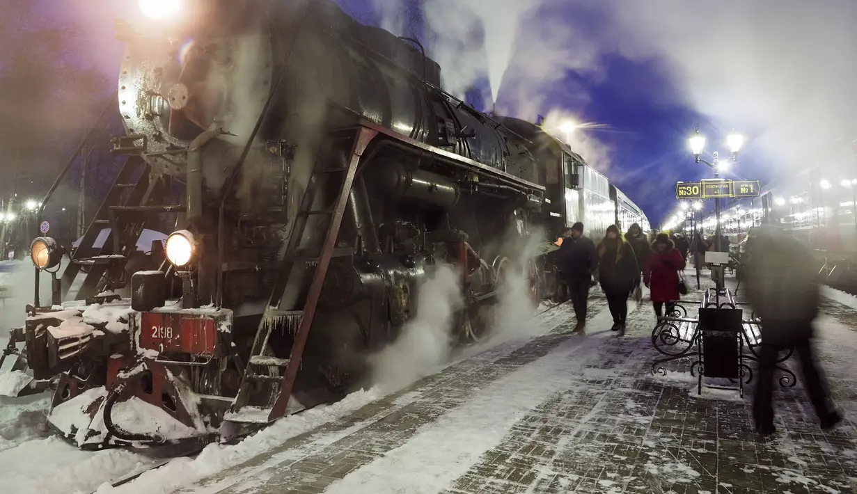 Penumpang berjalan melewati lokomotif uap era Soviet dari kereta retro tiba ke kota Sortavala sekitar 200 km (125 mil) utara St. Petersburg, Rusia (16/2/2021).  Kereta retro bertenaga uap tersebut beroperasi setiap hari di perbatasan Rusia dengan Karelia. (AP Photo/Dmitri Lovetsky)