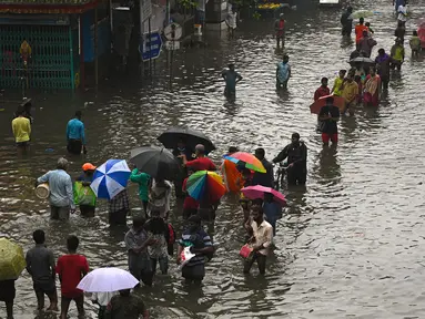 Orang-orang mengarungi jalan yang banjir setelah hujan lebat di Chennai, India (8/11/2021). Chennai dilanda Curah Hujan Terberat Sejak 2015,  Pihak berwenang Keluarkan Peringatan Banjir. (AFP/Arun Sankar)