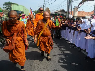 Murid sekolah dasar menyambut perjalanan rombongan 32 Biksu dari berbagai negara yang melakukan ritual Thudong dengan berjalan kaki menuju Candi Borobudur di Wiradesa, Kabupaten Pekalongan, Jawa Tengah, Kamis (25/5/2023). Ribuan warga menyambut perjalanan para biksu di sepanjang Jalan Pantura. (merdeka.com/Arie Basuki)