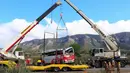 Dua crane dikerahkan untuk mengevakuasi sebuah bus di Jalan Raya AP7 dekat Kota Freginals, Spanyol, Minggu (20/3). Bus berisi 57 penumpang yang mayoritas mahasiswa asing itu terbalik ketika dalam perjalanan dari Valencia menuju Barcelona (PAU Barrena/AFP)