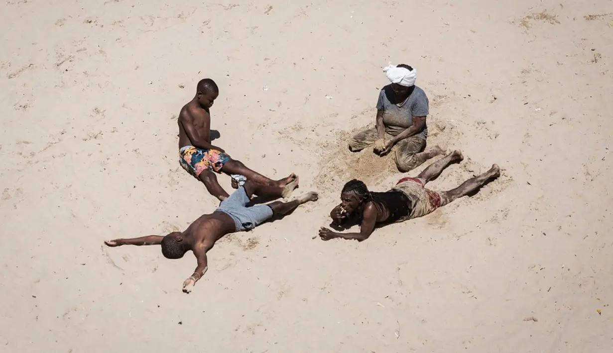 Wisatawan bersantai saat perayaan Tahun Baru di South Beach, Durban, Afrika Selatan, 1 Januari 2022. Pemerintah Afrika Selatan mencabut pembatasan COVID-19 dengan menghapus jam malam dari tengah malam hingga pukul 04.00. (Rajesh JANTILAL/AFP)
