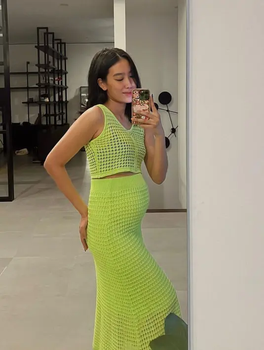 Memamerkan baby bump-nya lewat mirror selfie, Alika tampak chic mengenakan setelan knit ketat warna hijau neon.  (Instagram/alikaislamadina).