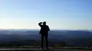 Seorang turis melihat ke Pegunungan Blue Ridge dekat Boone, Carolina Utara pada 19 Oktober 2021, saat musim gugur mulai menyelimuti dataran tinggi. (AP Photo/Gerry Broome)