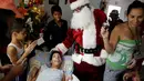 Santa Claus menghibur seorang anak berkebutuhan khusus saat mengunjungi kawasan kumuh Petare di Caracas, Venezuela (11/12). Kunjungan Santa Claus ini untuk menghibur anak-anak dalam menyambut datangnya natal. (Reuters/Ueslei Marcelino)