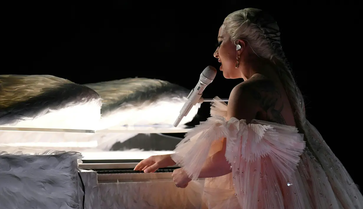 Penyanyi Lady Gaga tampil dengan piano putih berbalut sepasang sayap raksasa di panggung Grammy Awards 2018, New York,  Minggu (28/1). Penampilannya pun memukau dengan tantanan rambut pirang berkepang dengan tali hitam. (KEVIN WINTER/GETTY IMAGES/AFP)