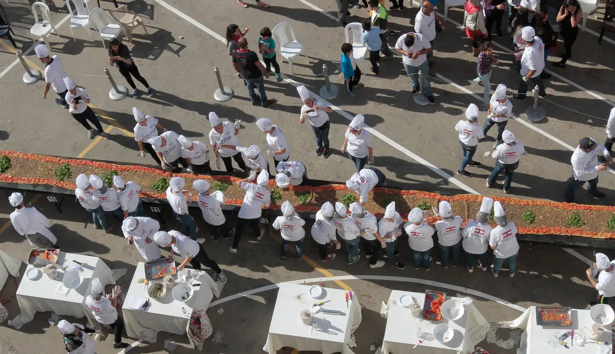 Peserta menyiapkan roti manousheh dengan rempah-rempah, wijen dan minyak zaitun, di Choueifat, Beirut, Lebanon (22/11). Roti terpanjang di dunia sebelumnya dipegang oleh Arab Saudi pada 2014 dan diukur 15,17 meter. (AFP PHOTO/STR)