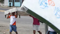 Penjarah membawa kasur yang baru saja mereka jarah dari sebuah toko di Managua, Nikaragua, Minggu (22/4). Pemerintah Nikaragua meningkatkan pajak dan memotong tunjangan pensiun dalam sistem jaminan sosial. (AP Photo/Alfredo Zuniga)