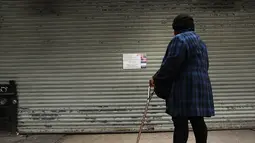 Seorang wanita melihat kertas pemberitahuan di pintu toko kelontong yang tutup di Brooklyn borough New York City, Kamis (2/1). Aksi pemogokan ini merupakan protes terhadap kebijakan imigrasi Donald Trump. (Spencer Paltt/GETTY IMAGES NORTH AMERICA/AFP)