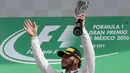 Pembalap tim Mercedes, Lewis Hamilton mengangkat trofi , setelah menjuarai balapan F1, di Grand Prix Meksiko yang berlangsung di Sirkuit Autodromo Hermanos Rodriguez, Mexico City, Meksiko (30/10). (Reuters/Henry Romero)