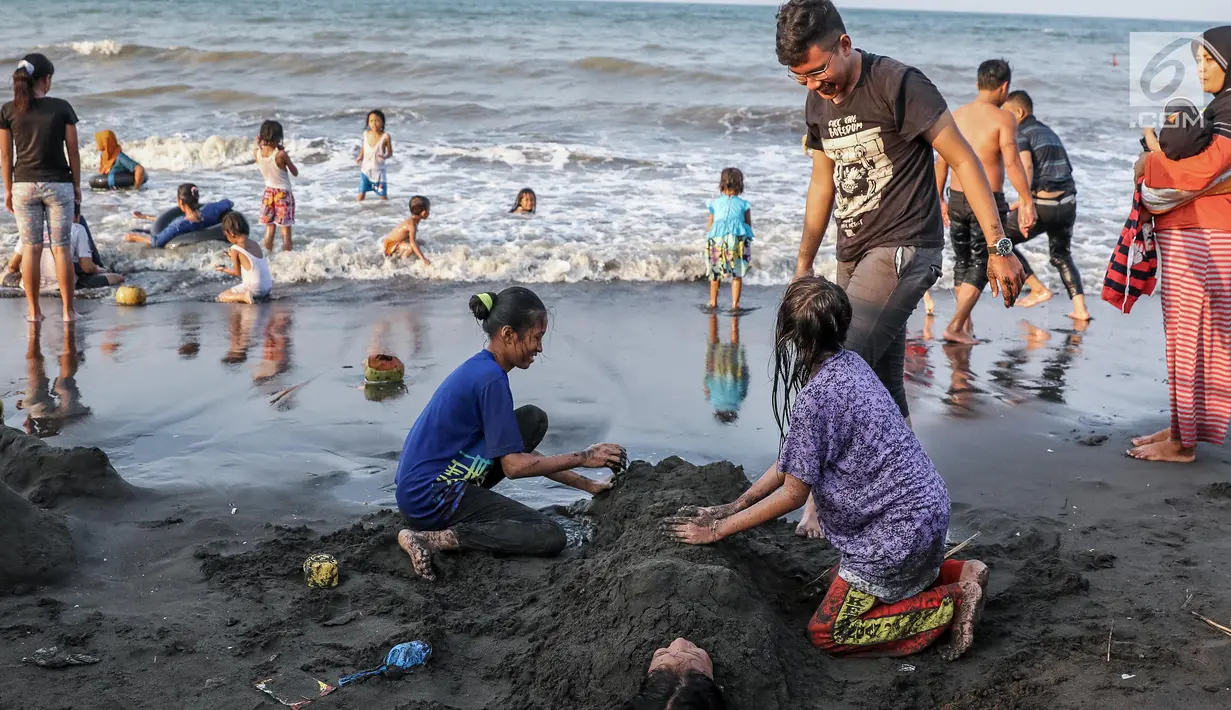 Pengunjung bermain pasir di Pantai Randusanga Indah, Brebes, Jawa Tengah, Minggu (2/7). Pantai Randusanga Indah ini juga menjadi tujuan wisata warga sekitar Brebes untuk mengisi waktu liburan lebaran. (Liputan6.com/Faizal Fanani)