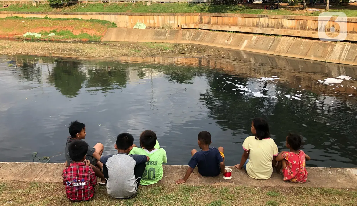 Anak-anak bermain di sekitar bantaran Kanal Banjir Timur (KBT), kawasan Cipinang Muara, Jakarta, Selasa (16/6/2020). Sebagian besar warga masih mengabaikan protokol kesehatan dengan tidak menjaga jarak serta tanpa menggunakan masker. (Liputan6.com/Immanuel Antonius)