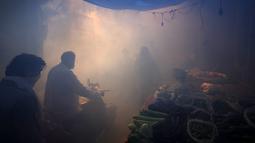 Komuter berjalan melewati asap dari fogging di daerah padat penduduk di New Delhi, India, Rabu (27/10/2021). New Delhi telah melaporkan ratusan kasus demam berdarah, dengan lebih dari 200 kasus baru dalam seminggu terakhir, menurut laporan yang dirilis pada hari Senin. (AP Photo/Manish Swarup)