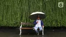 Seorang pria duduk sambil menggunakan payung saat hujan mengguyur kawasan Jakarta, Senin (3/2/2020). Diperkirakan sejumlah wilayah berpotensi diguyur hujan dengan intensitas lebat hingga disertai dengan angin kencang, kilat/petir hingga Rabu (5/2/2020) mendatang. (Liputan6.com/Angga Yuniar)