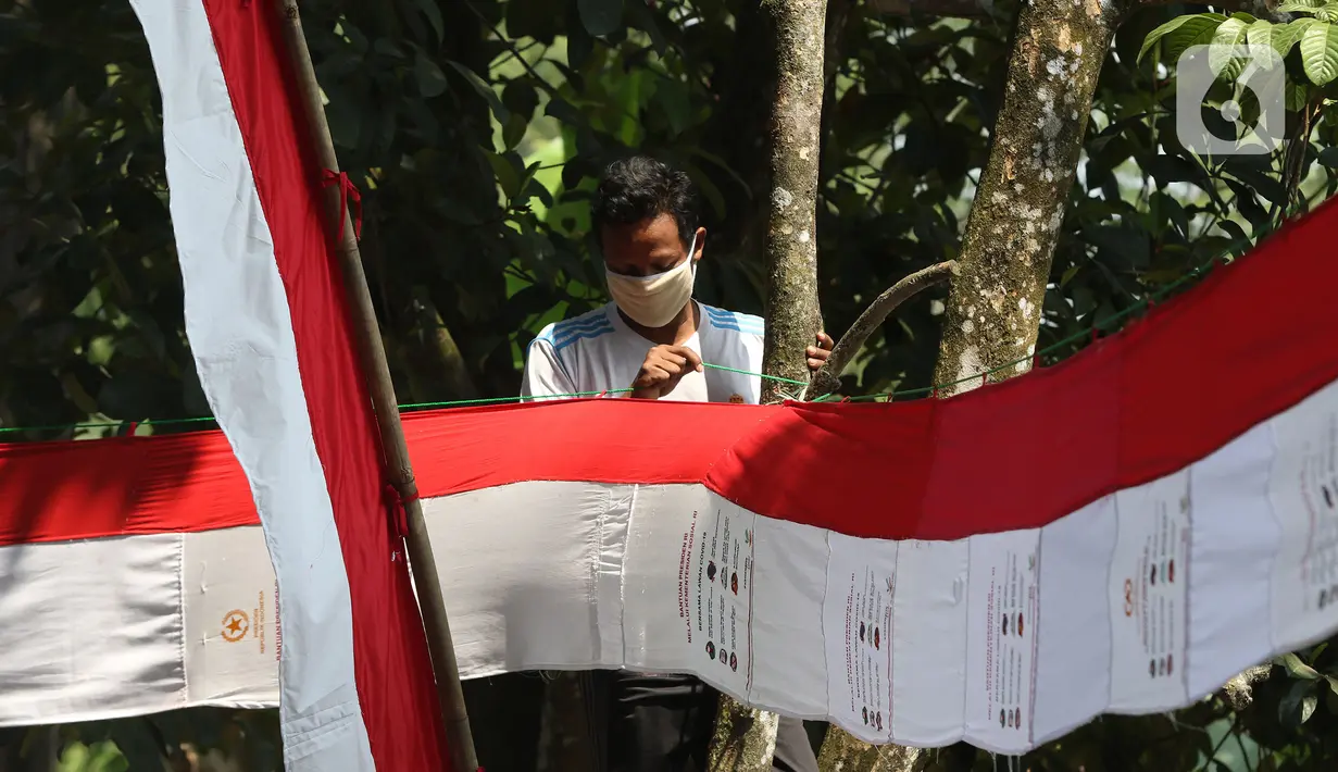 Warga memasang umbul-umbul dari tas sembako bantuan Presiden Joko Widodo di Jalan Caringin, Bedahan Barat, Sawangan, Depok, Jawa Barat, Jumat (7/8/2020). Bahan tas sembako berwarna merah putih tersebut dipasang sepanjang jalan Caringin untuk menyambut HUT ke-75 RI. (Liputan6.com/Herman Zakharia)