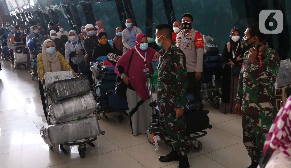 Sejumlah rombongan jemaah umrah diarahkan petugas setibanya di Bandara Soekarno Hatta, Tangerang, Selasa (29/12/2020). Rombongan jemaah umrah yang baru tiba di Indonesia tersebut harus melakukan karantina di tempat yang telah disediakan oleh pemerintah. (Liputan6.com/Angga Yuniar)