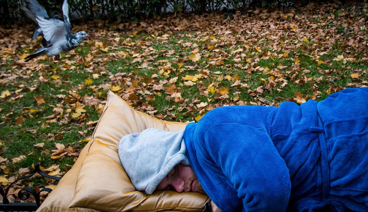 Aktivis tidur di bangku taman di pusat kota Bratislava untuk mengekspresikan solidaritas kepada tunawisma di Hungaria, 8 November 2018. Pasalnya tidur di tempat umum dilarang setelah undang-undang tunawisma diadopsi oleh pemerintah. (VLADIMIR SIMICEK/AFP)