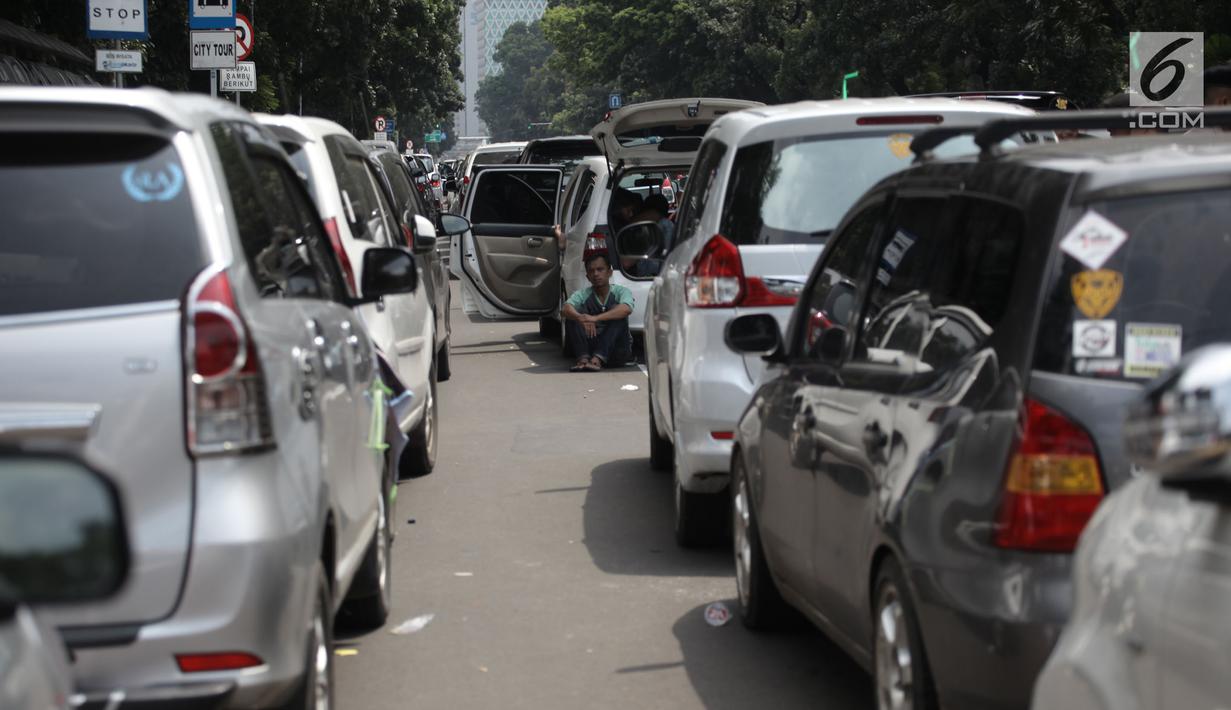 Seorang sopir sopir taksi online beristirahat saat demo di Jalan Medan Merdeka Barat, Jakarta, Rabu (14/2). Para pengemudi meminta Menteri Perhubungan Budi Karya untuk menghapus Permenhub Nomor 108 Tahun 2017. (Liputan6.com/Arya Manggala)