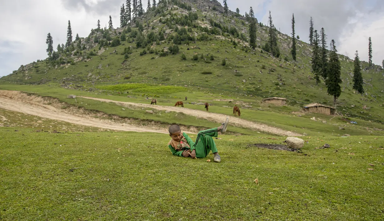Dawood Malik, seorang anak gembala Kashmir bereaksi terhadap kamera yang dia awasi pada ternaknya di Tosamaidan, barat daya Srinagar, Kashmir yang dikuasai India (21/6/2021). (AP Photo/Dar Yasin)