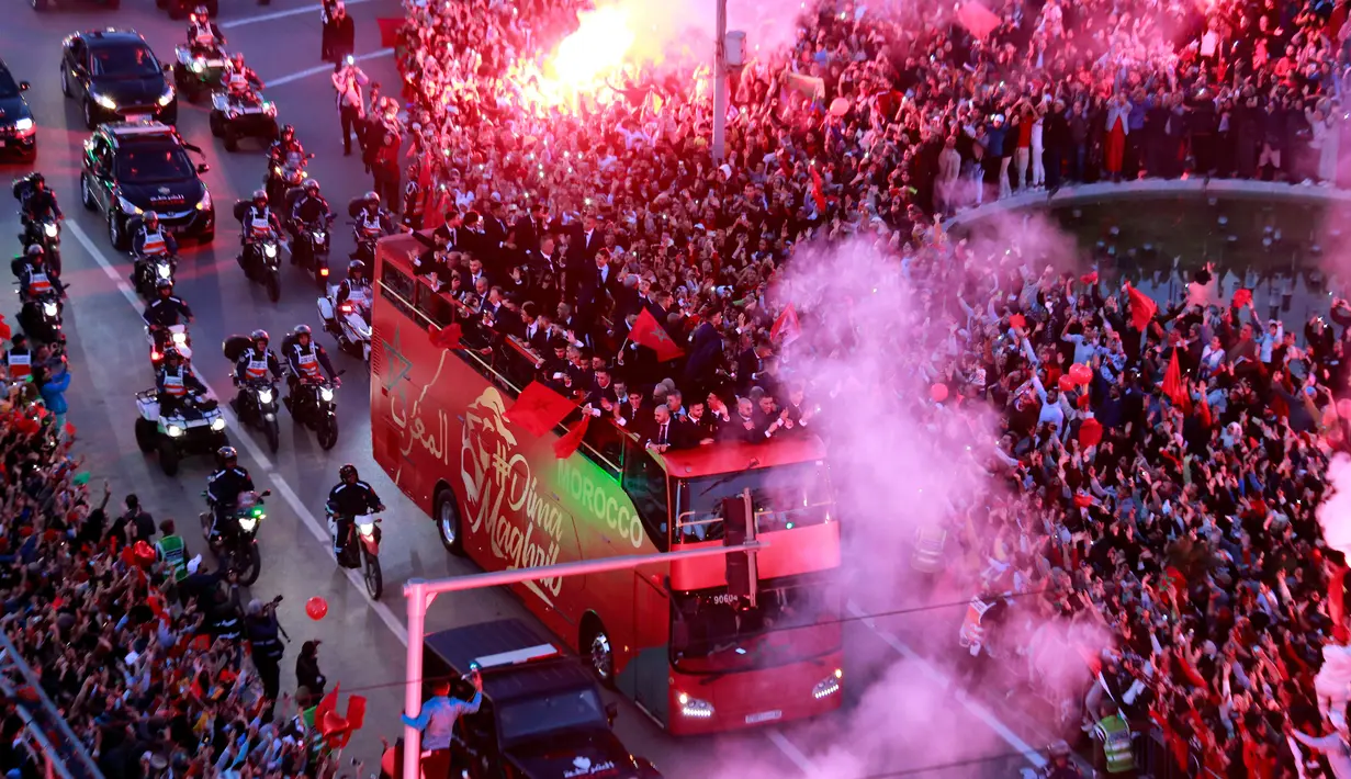 Warga melakukan perayaan saat parade Timnas Maroko di Rabat, Maroko, 20 Desember 2022. Timnas Maroko mendapat sambutan hangat di negaranya setelah berhasil meraih juara keempat Piala Dunia 2022. (AP Photo)