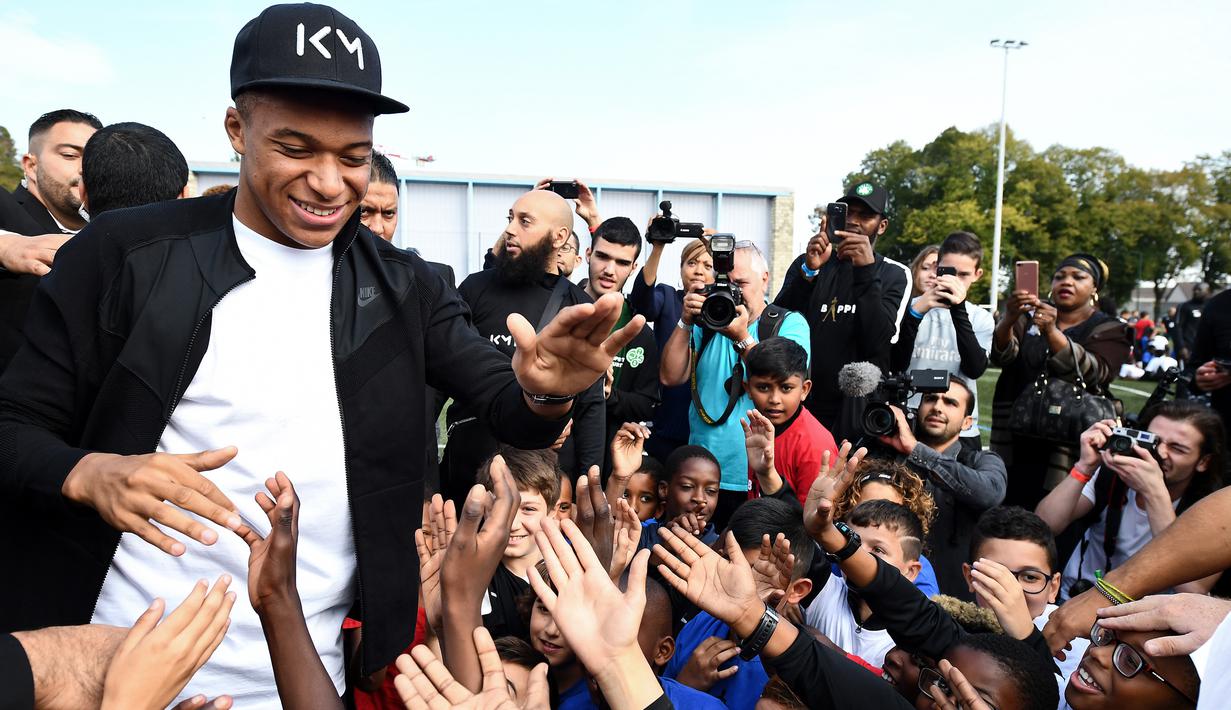 Bintang Prancis, Kylian Mbappe, menyapa anak-anak saat mengunjungi markas AS Bondy di Paris, Rabu (17/10). Kunjungan ke klub pertamanya ini dilakukan setelah dirinya meraih gelar Piala Dunia 2018. (AFP/Franck Fife)